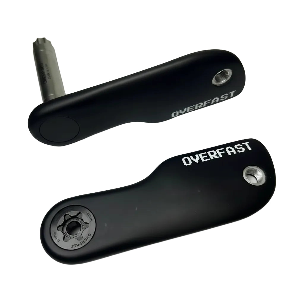 Two black bicycle crank arms with silver bolts and a silver hex key, shown on a light gray background. One crank arm has 'OVERFAST' printed on it in white.